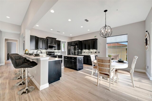 23233 Banbury Way Unit 302, Venice, FL 34293 - kitchen featuring stainless steel appliances, dark cabinets, light countertops, backsplash, and a center island