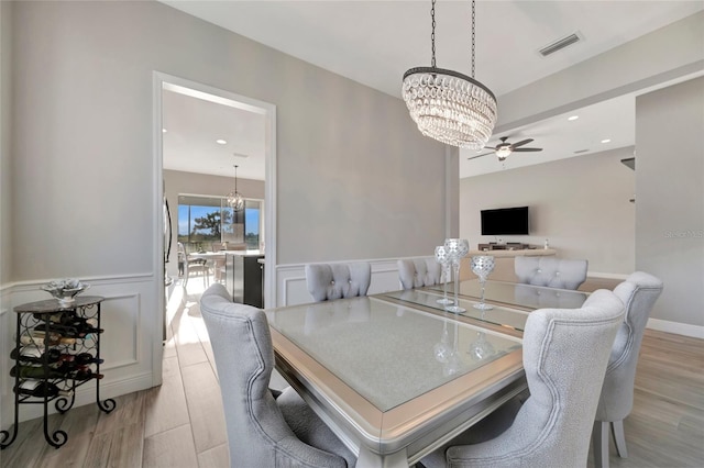 23233 Banbury Way Unit 302, Venice, FL 34293 - dining space with a chandelier, wood finished floors, wainscoting, a ceiling fan, and a decorative wall