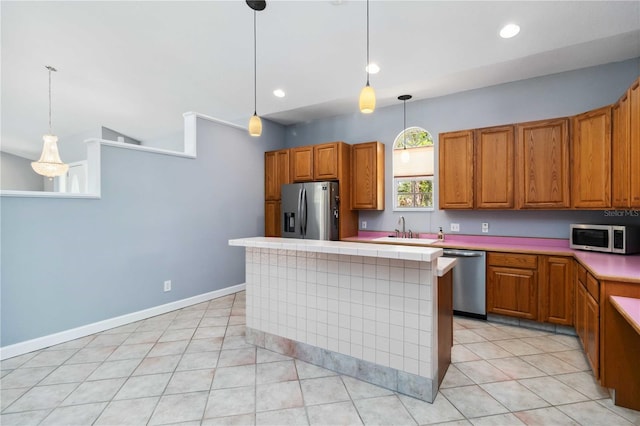 296 Pine Ranch Trl, Osprey, FL 34229 - kitchen with stainless steel appliances, a sink, light countertops, brown cabinetry, and a kitchen island