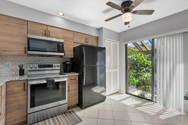 4505 Kingsmere Unit 2, Sarasota, FL 34235 - kitchen featuring stainless steel appliances, backsplash, brown cabinets, light tile patterned floors, and light stone counters