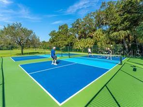 4505 Kingsmere Unit 2, Sarasota, FL 34235 - view of tennis court with community basketball court and view of scattered trees