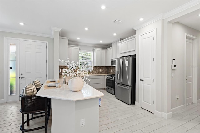15707 Sacile Ln, Bradenton, FL 34211 - kitchen featuring stainless steel appliances, a peninsula, backsplash, a kitchen breakfast bar, and white cabinets