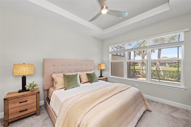 15707 Sacile Ln, Bradenton, FL 34211 - bedroom with light colored carpet, baseboards, a tray ceiling, and a ceiling fan