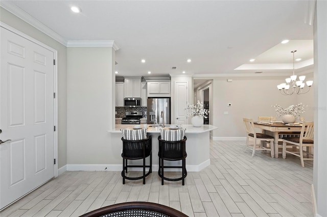 15707 Sacile Ln, Bradenton, FL 34211 - kitchen featuring appliances with stainless steel finishes, light countertops, baseboards, light wood-style floors, and ornamental molding