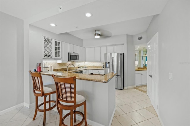 1280 Dolphin Bay Way Unit 204, Sarasota, FL 34242 - kitchen with appliances with stainless steel finishes, light stone countertops, a peninsula, glass insert cabinets, and white cabinets