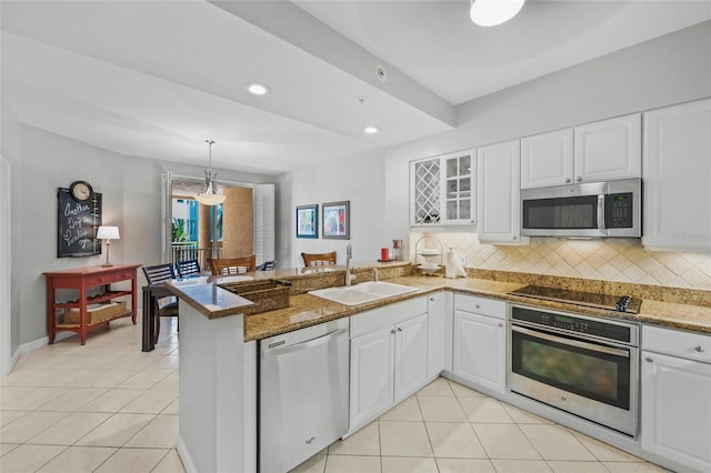 1280 Dolphin Bay Way Unit 204, Sarasota, FL 34242 - kitchen with stainless steel appliances, a sink, a peninsula, light tile patterned floors, and decorative backsplash