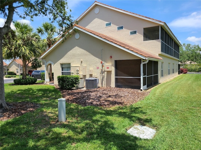 7273 Cedar Hollow Cir Unit 102, Bradenton, FL 34203 - rear view of property with a sunroom, stucco siding, central AC unit, and a lawn
