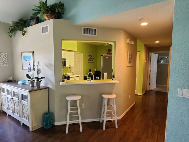 7273 Cedar Hollow Cir Unit 102, Bradenton, FL 34203 - kitchen featuring dark wood-type flooring, a breakfast bar, white cabinetry, range, and a textured wall