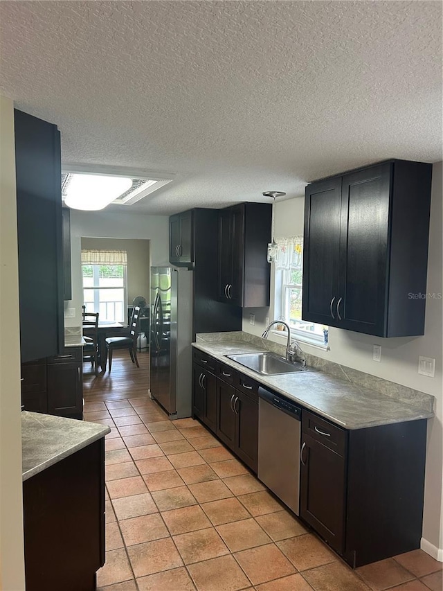 3287 Rackley Rd, Brooksville, FL 34604 - kitchen featuring a sink, stainless steel appliances, light tile patterned floors, a textured ceiling, and dark cabinets