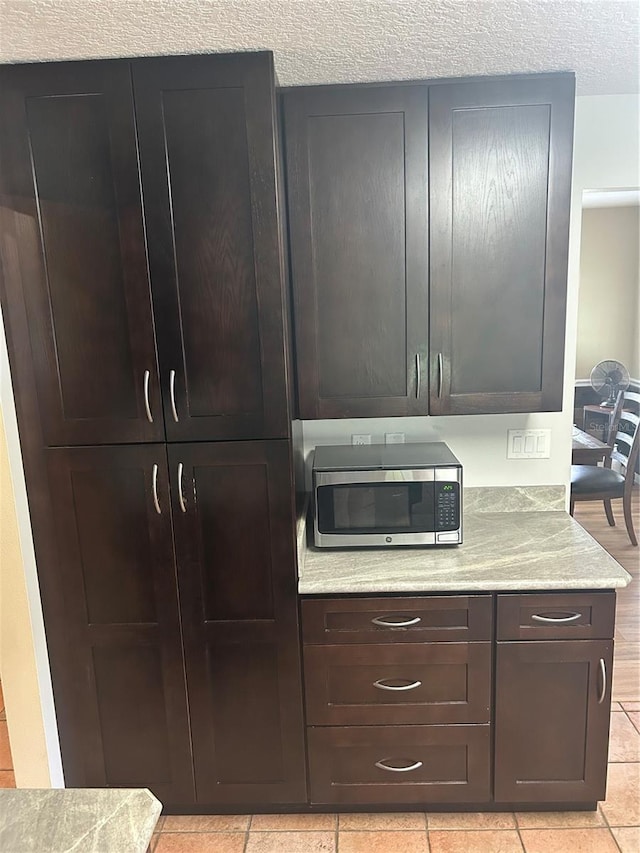 3287 Rackley Rd, Brooksville, FL 34604 - detailed view of stainless steel microwave, a textured ceiling, light stone countertops, and dark brown cabinets
