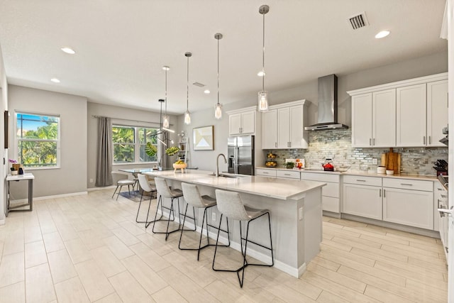 5718 Title Row Dr, Bradenton, FL 34210 - kitchen with wall chimney exhaust hood, stainless steel fridge with ice dispenser, backsplash, a kitchen breakfast bar, and white cabinets