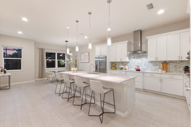 5718 Title Row Dr, Bradenton, FL 34210 - kitchen featuring wall chimney range hood, high quality fridge, tasteful backsplash, a kitchen bar, and a kitchen island with sink