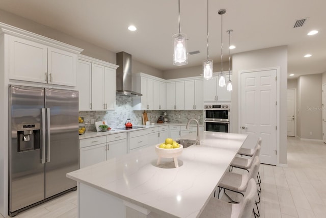 5718 Title Row Dr, Bradenton, FL 34210 - kitchen with appliances with stainless steel finishes, wall chimney exhaust hood, tasteful backsplash, white cabinetry, and pendant lighting