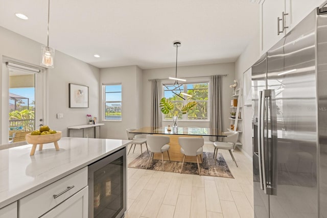5718 Title Row Dr, Bradenton, FL 34210 - kitchen featuring stainless steel fridge, wine cooler, healthy amount of natural light, white cabinets, and recessed lighting
