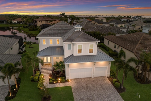 5718 Title Row Dr, Bradenton, FL 34210 - view of front of home featuring decorative driveway, a water view, stucco siding, and a front lawn