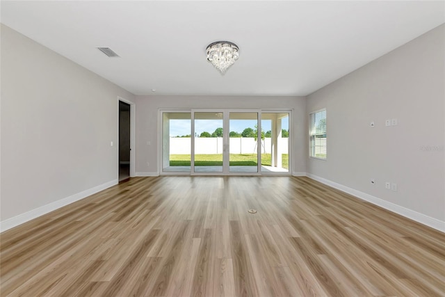 12613 Oak Hill Way, Parrish, FL 34219 - unfurnished room with baseboards, healthy amount of natural light, a chandelier, and light wood-type flooring