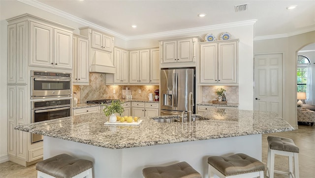 5622 Arnie Loop, Lakewood Ranch, FL 34211 - kitchen with appliances with stainless steel finishes, arched walkways, a breakfast bar, a sink, and premium range hood