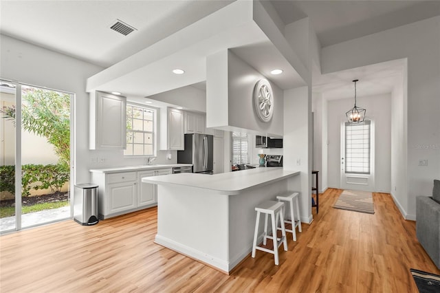 7716 Uliva Way, Sarasota, FL 34238 - kitchen featuring stainless steel appliances, light wood-style flooring, light countertops, a kitchen bar, and recessed lighting