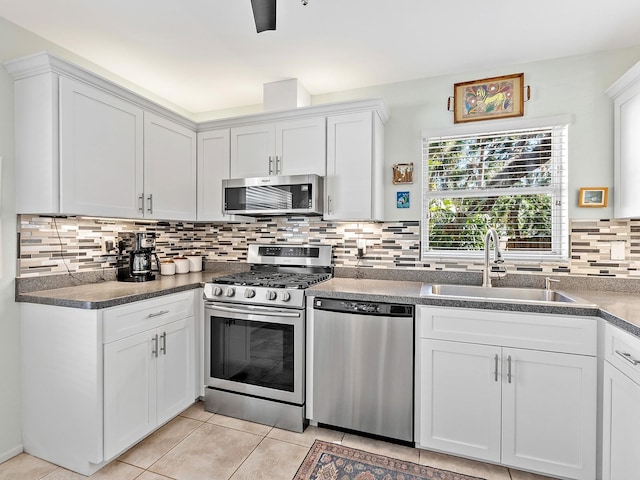 4869 Village Gardens Dr Unit 189, Sarasota, FL 34234 - kitchen featuring appliances with stainless steel finishes, backsplash, white cabinetry, light tile patterned flooring, and dark countertops