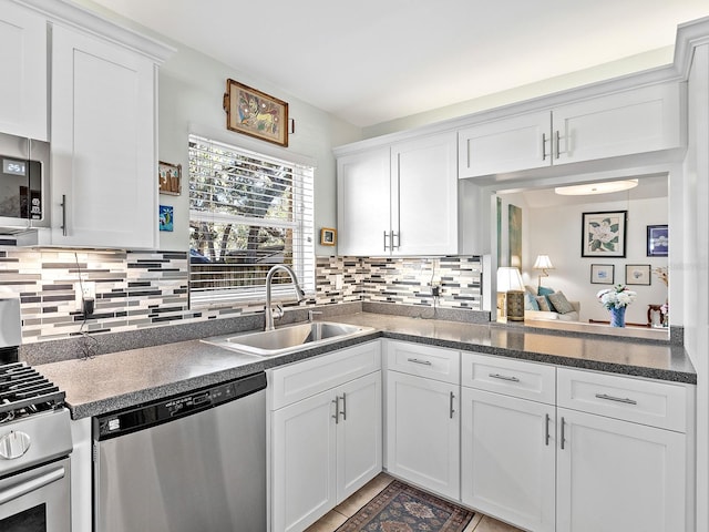 4869 Village Gardens Dr Unit 189, Sarasota, FL 34234 - kitchen with appliances with stainless steel finishes, white cabinets, backsplash, and dark countertops