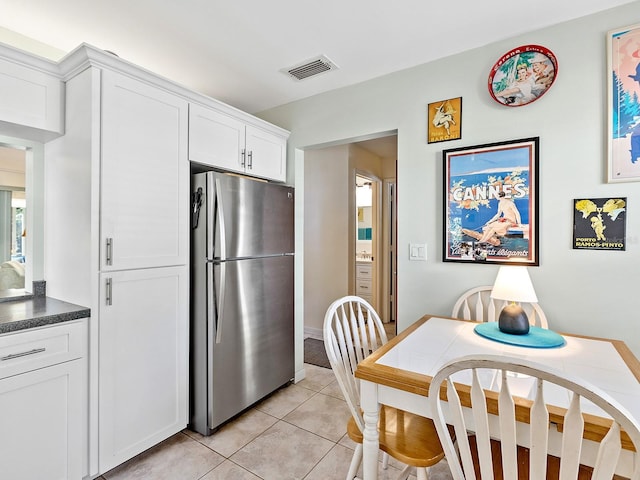 4869 Village Gardens Dr Unit 189, Sarasota, FL 34234 - kitchen with freestanding refrigerator, light tile patterned floors, dark countertops, and white cabinetry