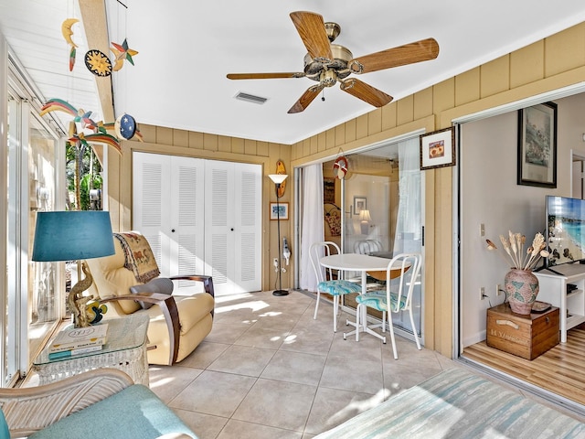 4869 Village Gardens Dr Unit 189, Sarasota, FL 34234 - living room with light tile patterned floors, a ceiling fan, and wood walls
