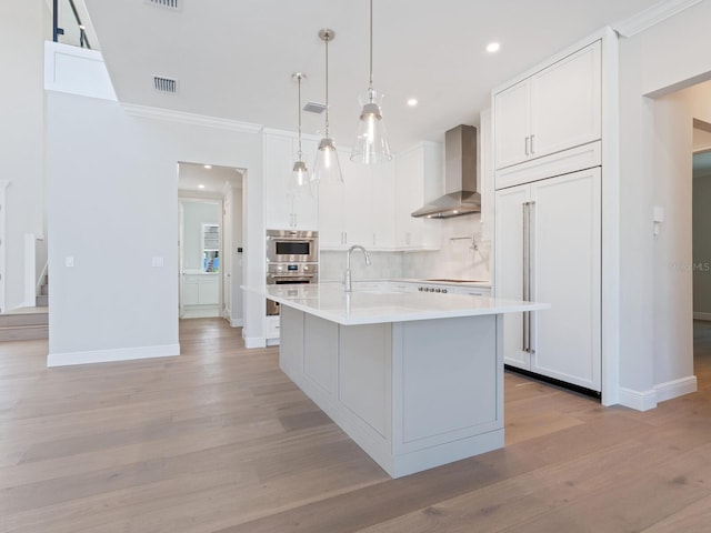 430 Pheasant Way, Sarasota, FL 34236 - kitchen featuring wall chimney exhaust hood, paneled refrigerator, crown molding, light wood-style flooring, and white cabinetry