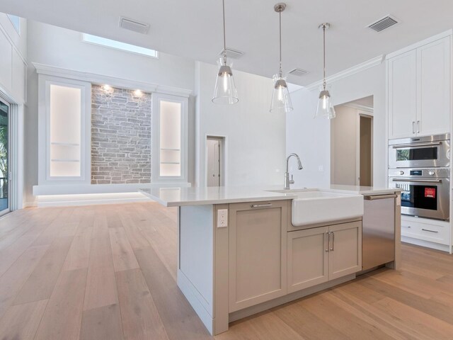 430 Pheasant Way, Sarasota, FL 34236 - kitchen featuring light wood-style flooring, light countertops, pendant lighting, stainless steel appliances, and a kitchen island with sink