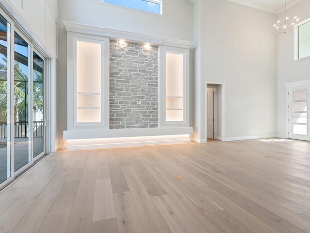 430 Pheasant Way, Sarasota, FL 34236 - unfurnished room with a towering ceiling, a chandelier, light wood finished floors, plenty of natural light, and crown molding