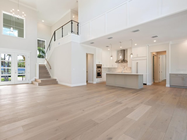 430 Pheasant Way, Sarasota, FL 34236 - unfurnished living room with a high ceiling, ornamental molding, french doors, light wood finished floors, and a chandelier