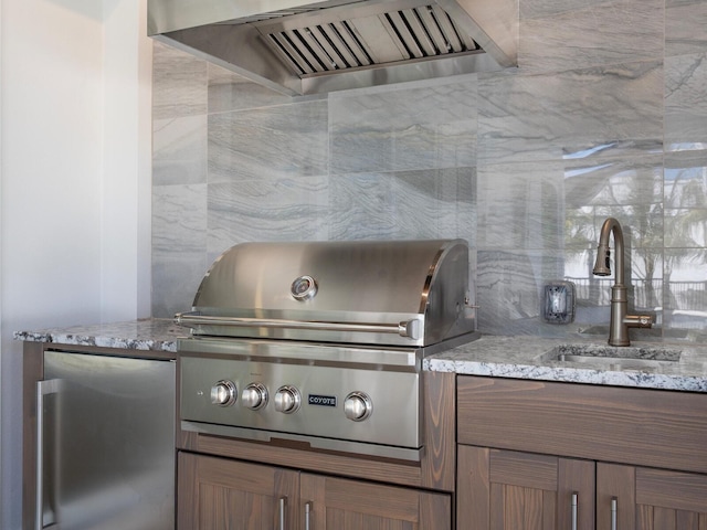 430 Pheasant Way, Sarasota, FL 34236 - kitchen with fridge, wall chimney exhaust hood, light stone countertops, and decorative backsplash
