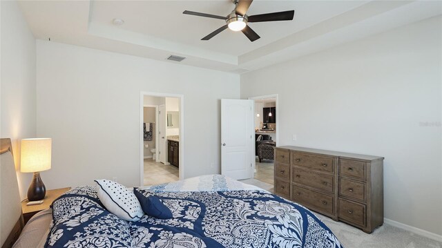 7379 47th Avenue Cir E, Bradenton, FL 34203 - bedroom with a tray ceiling, light colored carpet, baseboards, connected bathroom, and ceiling fan