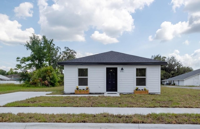 view of front facade with a front yard and roof with shingles