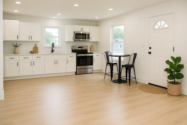 kitchen with stainless steel appliances, light wood-type flooring, a sink, plenty of natural light, and recessed lighting