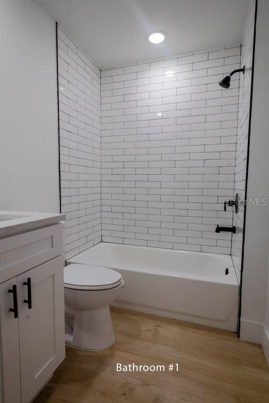 bathroom with toilet, vanity, shower / washtub combination, and wood finished floors