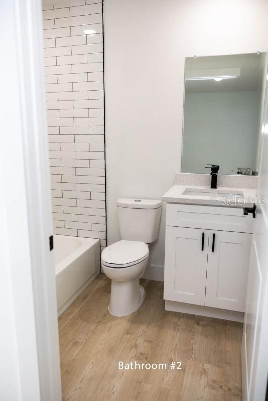 full bath with wood finished floors, toilet, and vanity