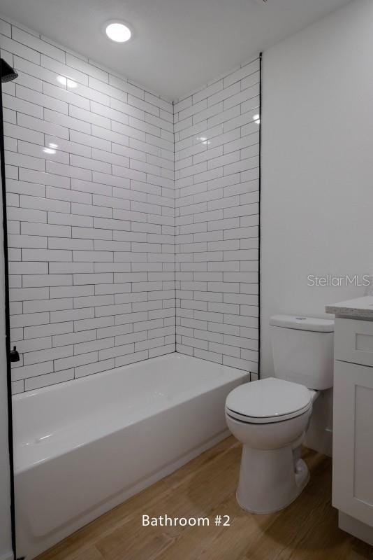 bathroom featuring wood finished floors, toilet, vanity, and  shower combination