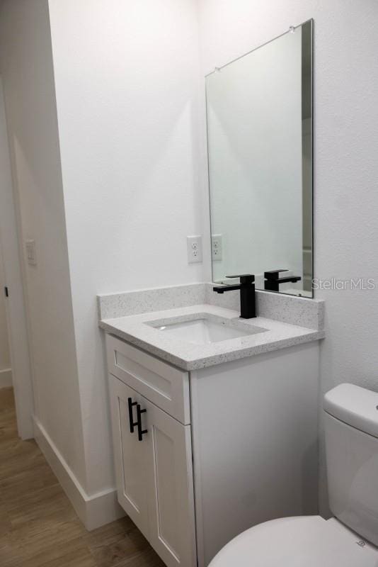 bathroom featuring toilet, vanity, and wood finished floors