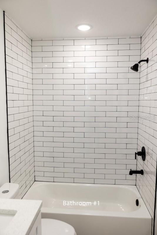 full bathroom featuring toilet, bathing tub / shower combination, and vanity