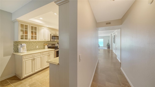 19 Whispering Sands Dr Unit 805, Sarasota, FL 34242 - kitchen with stainless steel appliances, cream cabinetry, baseboards, and backsplash