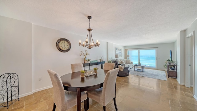 19 Whispering Sands Dr Unit 805, Sarasota, FL 34242 - dining area featuring stone tile floors, a chandelier, baseboards, and a textured ceiling