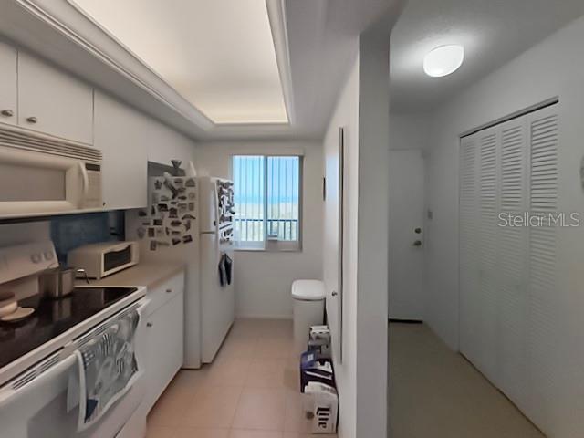 8977 Midnight Pass Rd Unit 521, Sarasota, FL 34242 - kitchen featuring white appliances, white cabinets, light countertops, and a tray ceiling