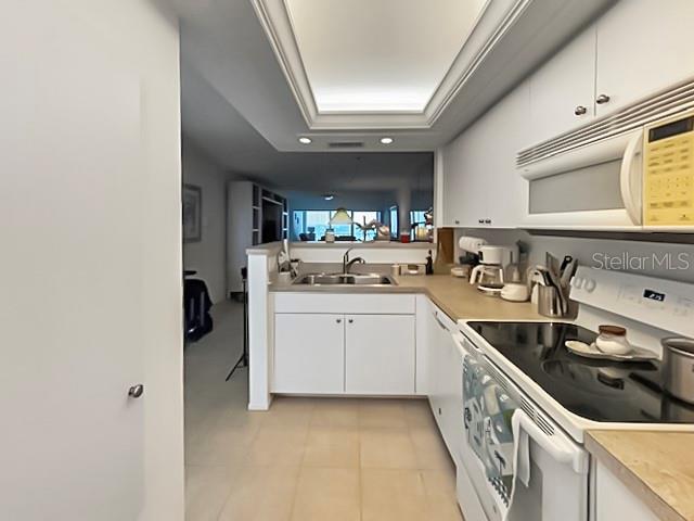 8977 Midnight Pass Rd Unit 521, Sarasota, FL 34242 - kitchen featuring white appliances, a sink, white cabinetry, light countertops, and a tray ceiling