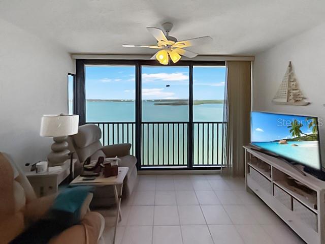 8977 Midnight Pass Rd Unit 521, Sarasota, FL 34242 - living area featuring a ceiling fan, light tile patterned floors, and expansive windows