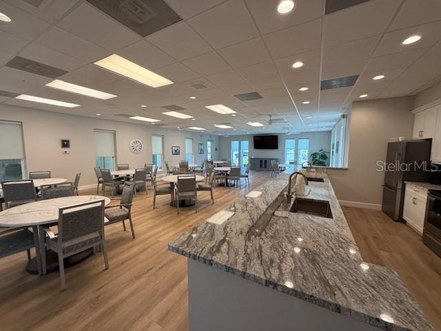 8977 Midnight Pass Rd Unit 521, Sarasota, FL 34242 - kitchen featuring a sink, light wood finished floors, white cabinets, freestanding refrigerator, and stone countertops