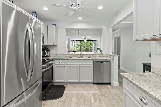 157 Pinehurst Dr Unit 157, Bradenton, FL 34210 - kitchen featuring appliances with stainless steel finishes, a sink, ceiling fan, light wood finished floors, and light stone counters