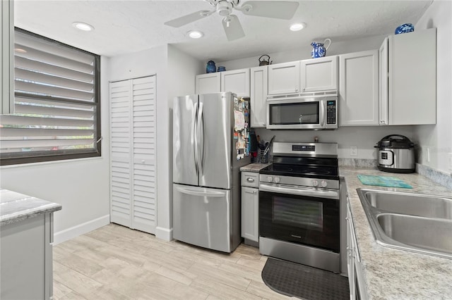 157 Pinehurst Dr Unit 157, Bradenton, FL 34210 - kitchen with stainless steel appliances, a sink, a ceiling fan, light wood-type flooring, and light countertops
