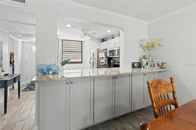 157 Pinehurst Dr Unit 157, Bradenton, FL 34210 - kitchen with stainless steel appliances, light wood-type flooring, a peninsula, light stone countertops, and crown molding