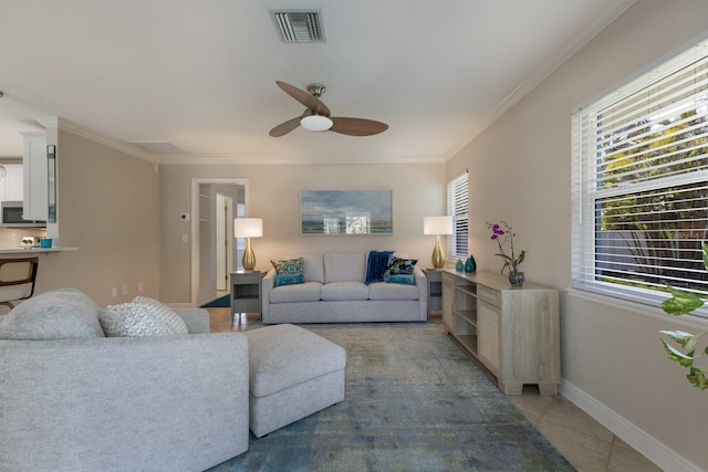 living area featuring healthy amount of natural light, ceiling fan, ornamental molding, baseboards, and light tile patterned flooring