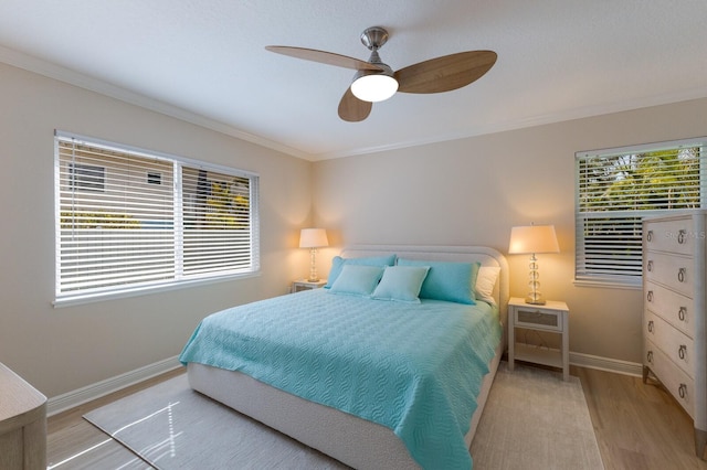 bedroom with wood finished floors, ornamental molding, baseboards, multiple windows, and ceiling fan